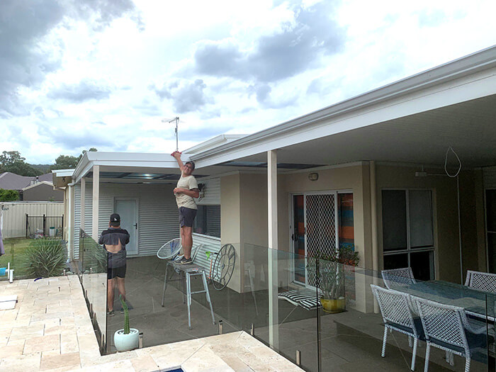 A man on a small scaffold cleaning gutters