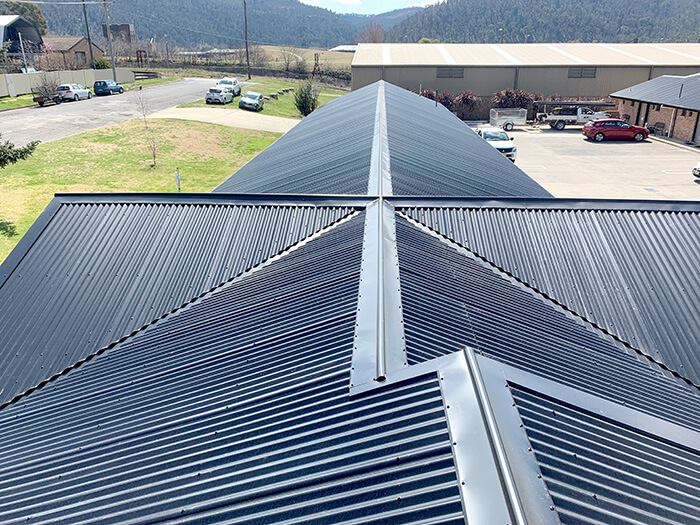 Looking down the spine of a new, dark, Colorbond roof with many intersecting angles