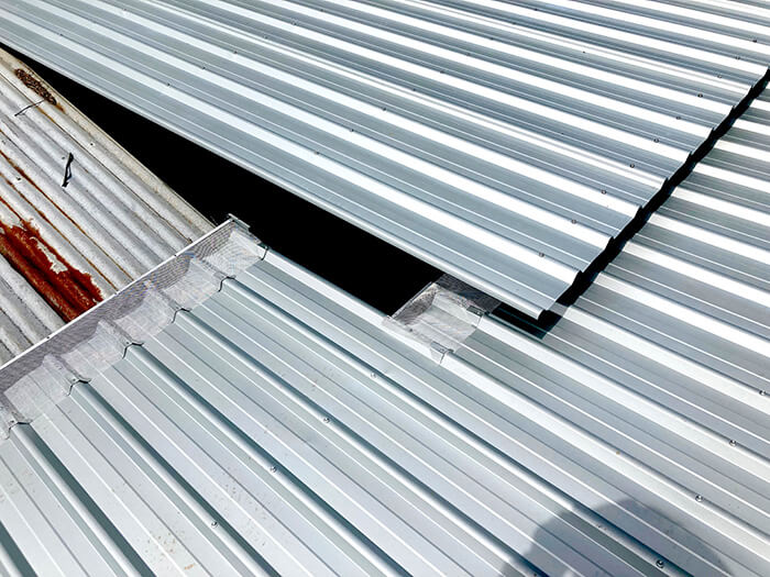 New roofing looking bright and shiny next to old rusty corrugated iron