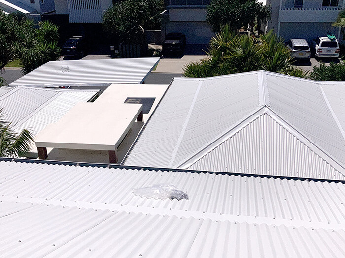A view down over several different sections of a building, all with new corrugated iron roofs